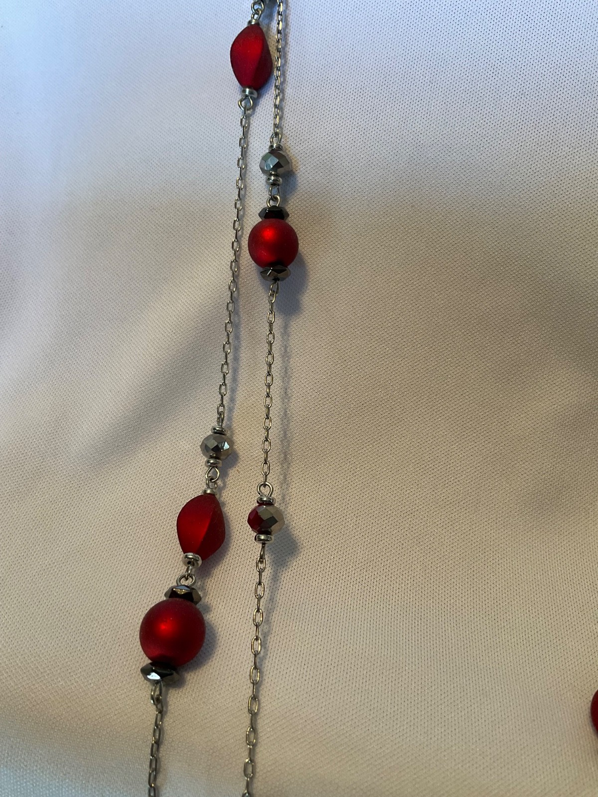 Marked “ruby red”. Necklace features red beads with glassy beads on silver chn